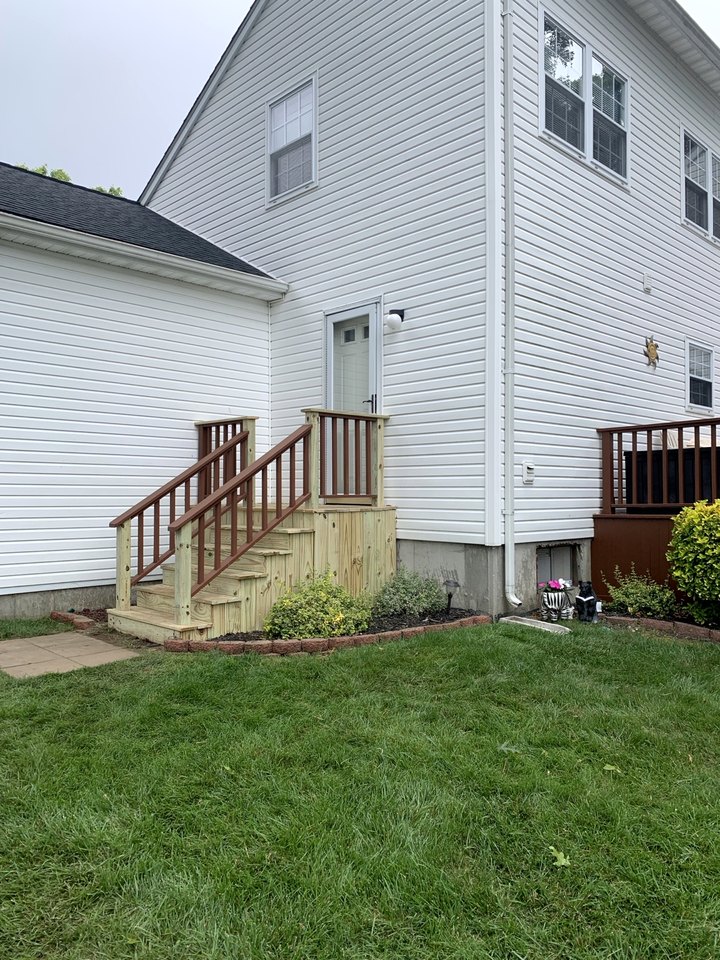 Rebuilt deck stair with a new railing, treads and balustrade meeting planted beds