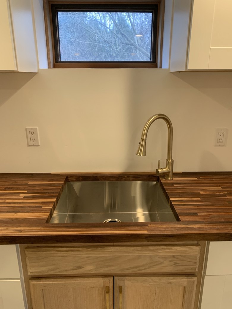 Installed lower cabinets with a walnut counter routed for an undermount stainless sink and drilled for a brushed brass faucet