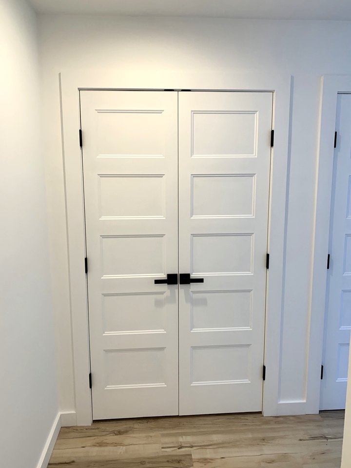 A pair of painted five-panel doors with matching black lever hardware