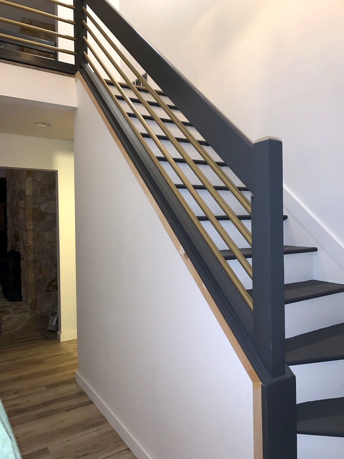 Painted staircase with new trim meeting a dark horizontal-bar railing