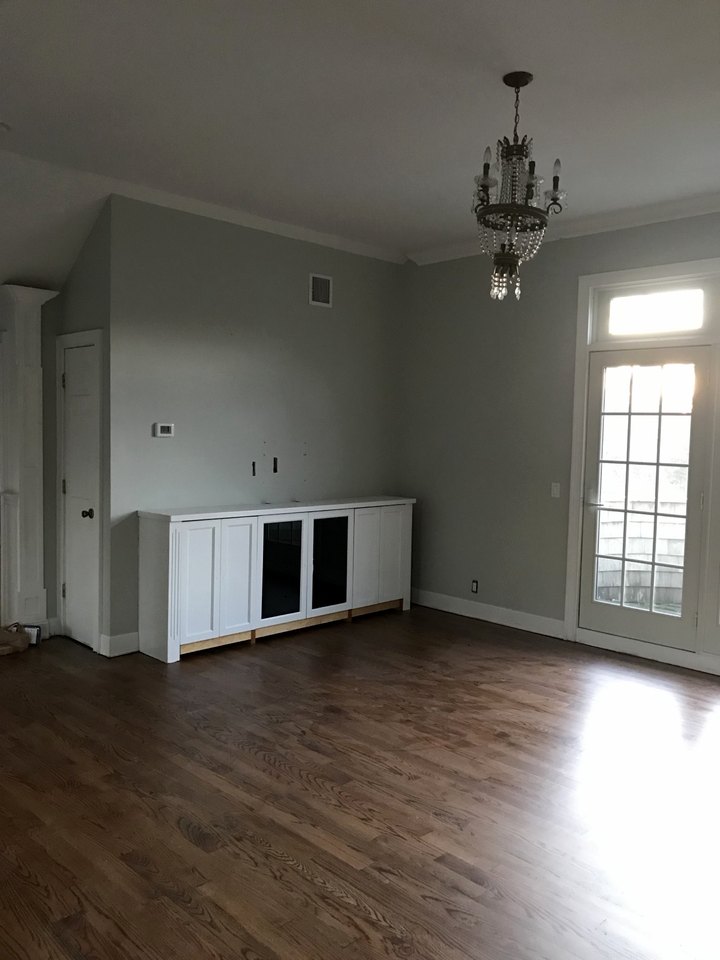 Living room with refinished oak floors and a painted cabinet beneath the window