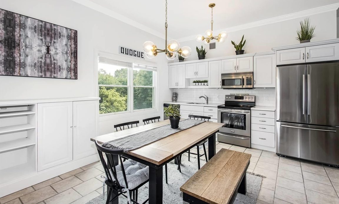 Kitchen with painted cabinetry and open shelving beside a dining table under a chandelier